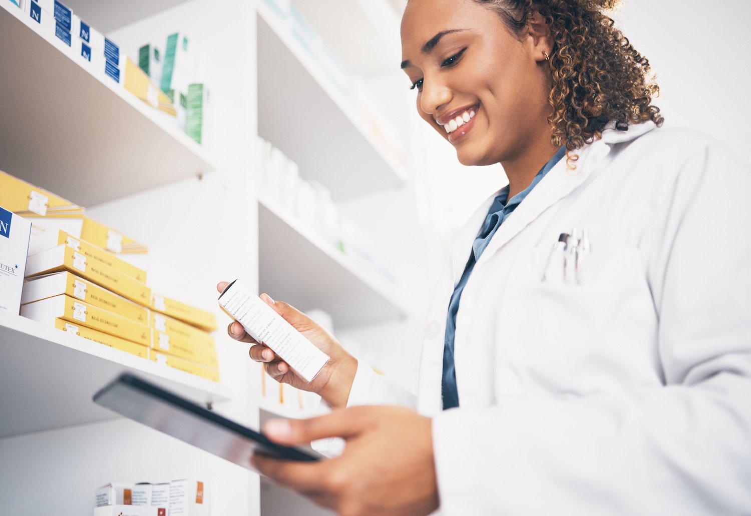 Female pharmacist smiling and holding a box of medication